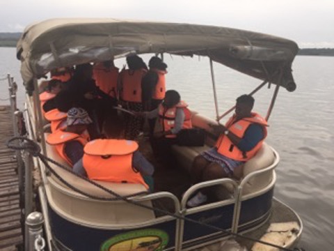 Ferry riders with bright orange life vests on a ferry on a body of water