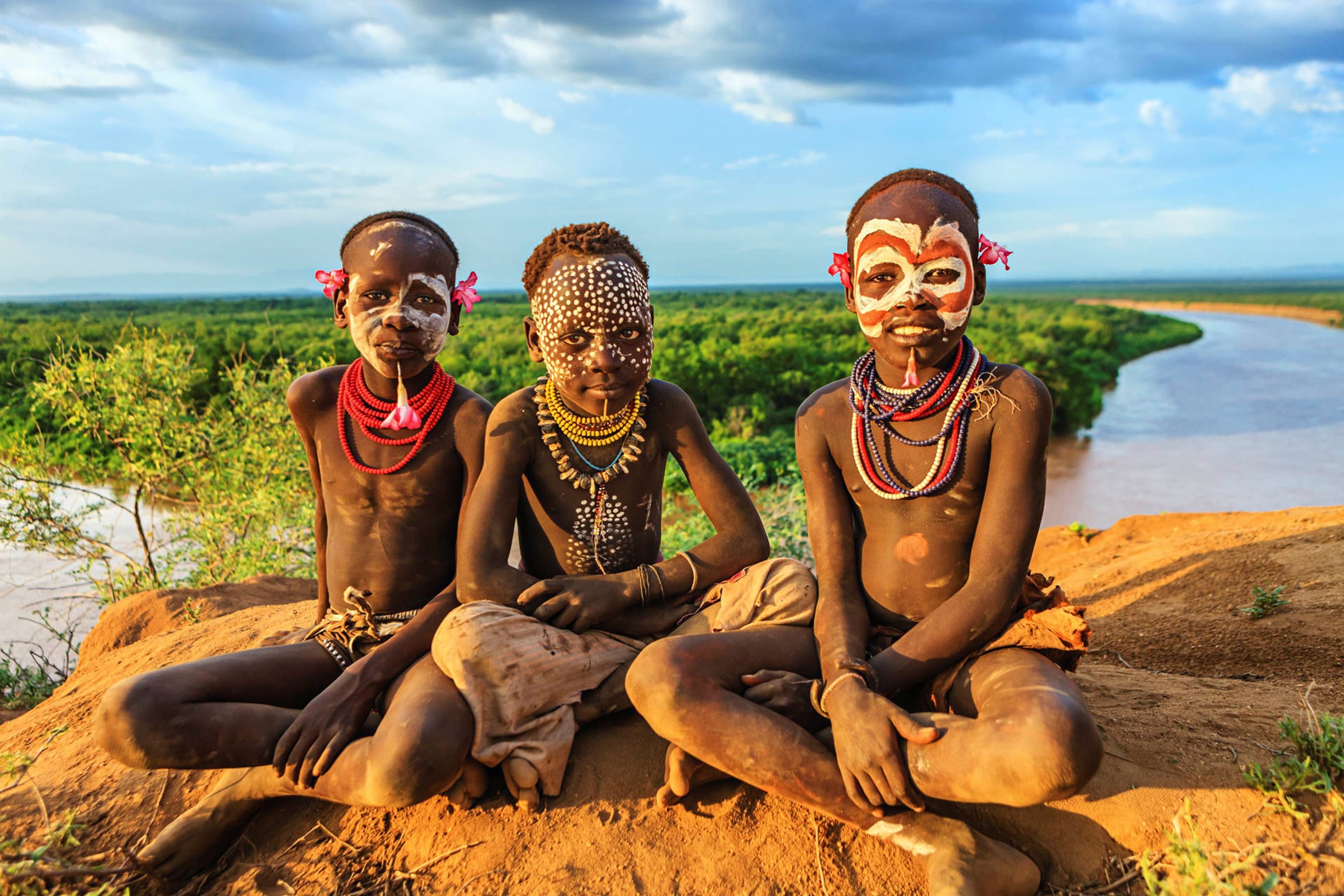 Three children donning traditional African attire and face paint