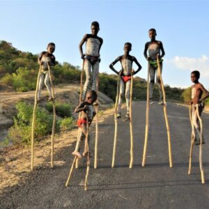 Children walking on wooden stilts on the road