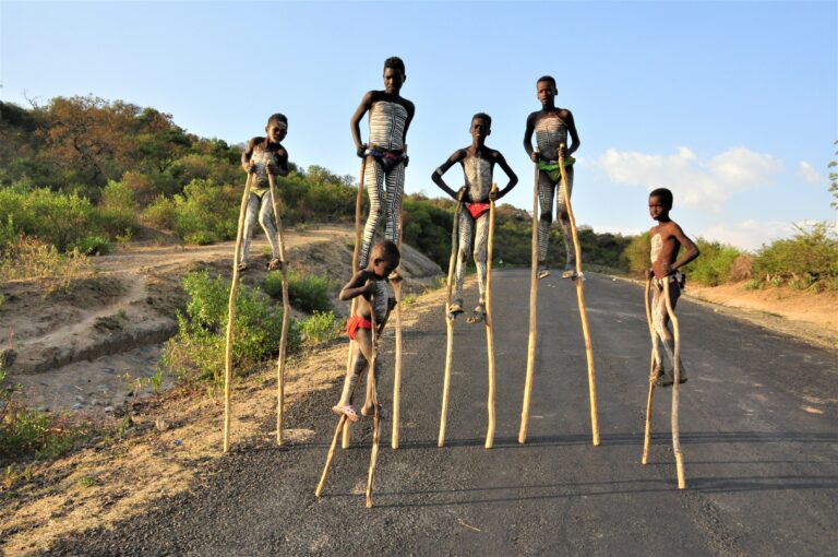 Children walking on wooden stilts on the road