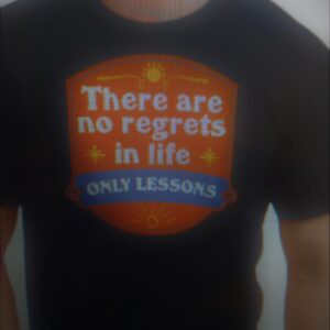 A black shirt with an orange guild logo that reads, "There are no regrets in life only lessons"